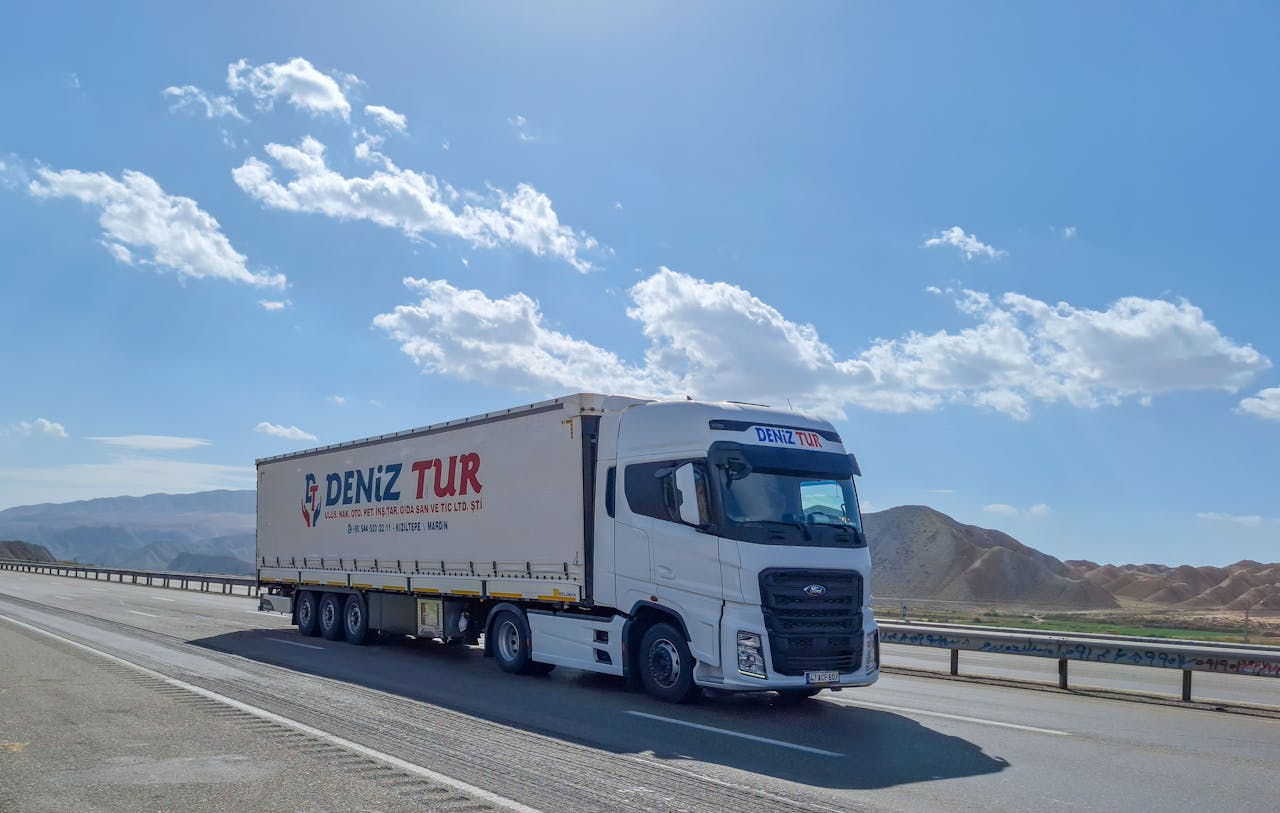 gallery-1 A Deniz Tur truck travels on a sunny highway in Tabriz, Iran, showcasing logistics on the road.