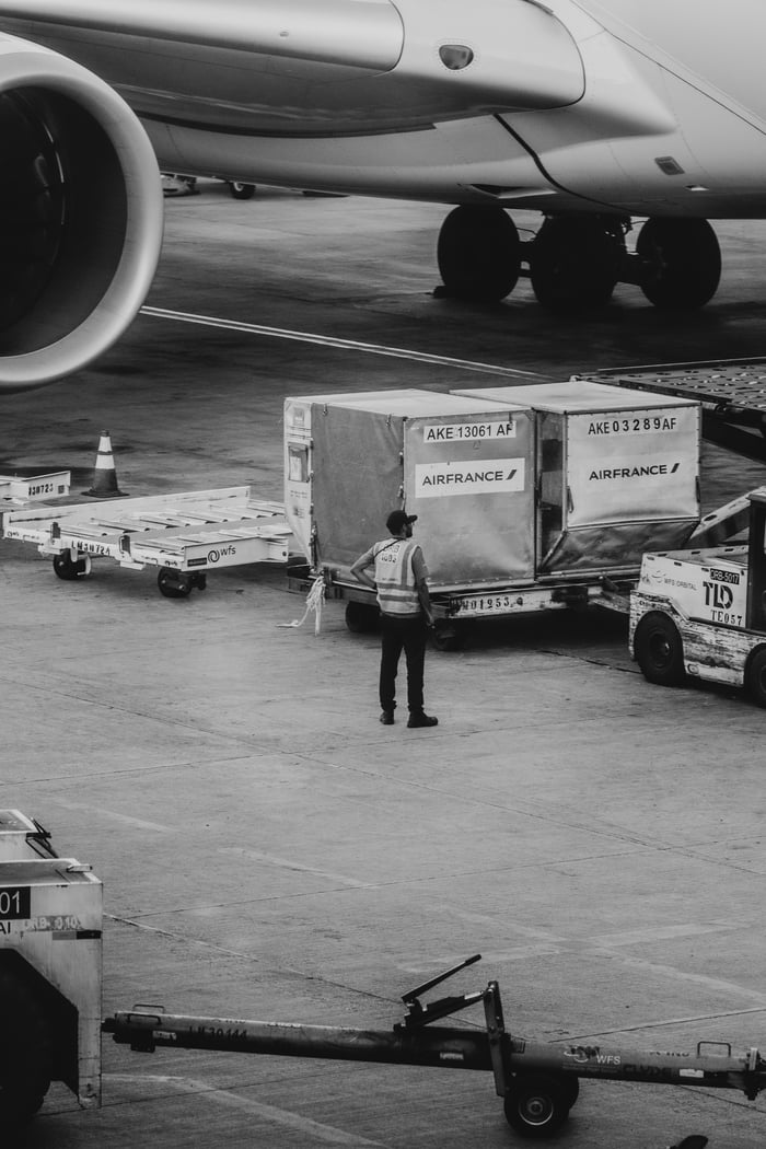 gallery-3 Black and white image of airport crew managing cargo near airplane