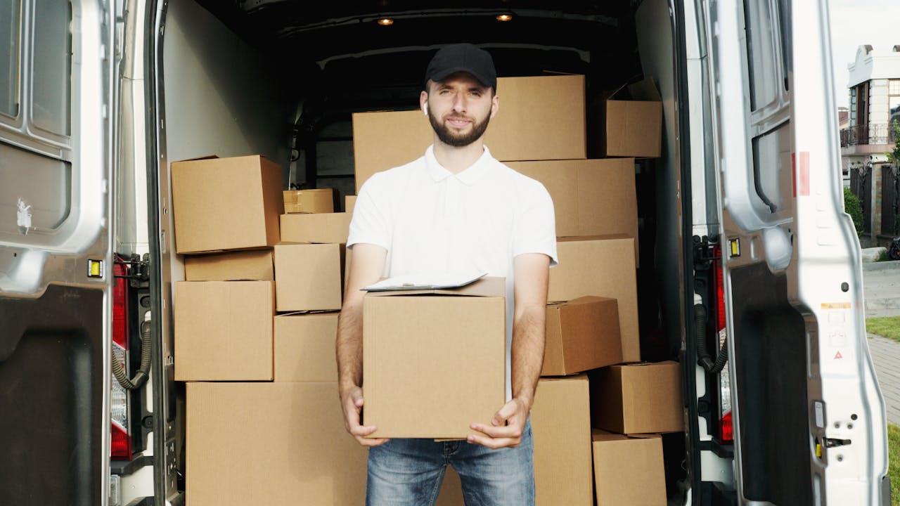 gallery-5 A courier standing at the back of a van holding a package for delivery.